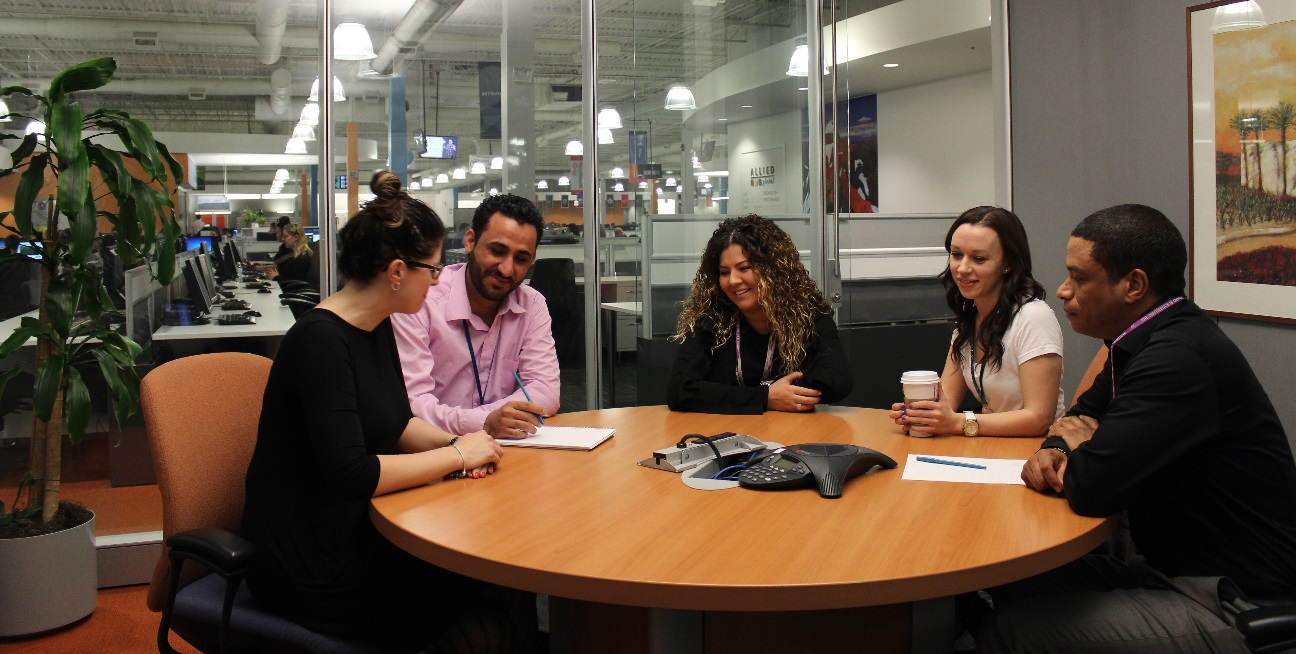 Four smiling people sitting around a boardroom table.